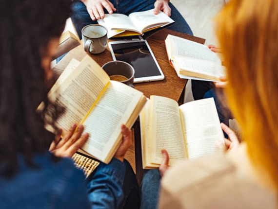 Diverse group of friends discussing a book in library.
