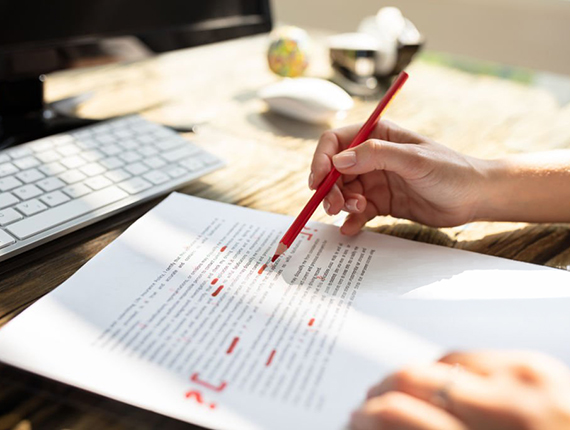 Close-up Of A Person's Hand Marking Error With Red Marker On Document